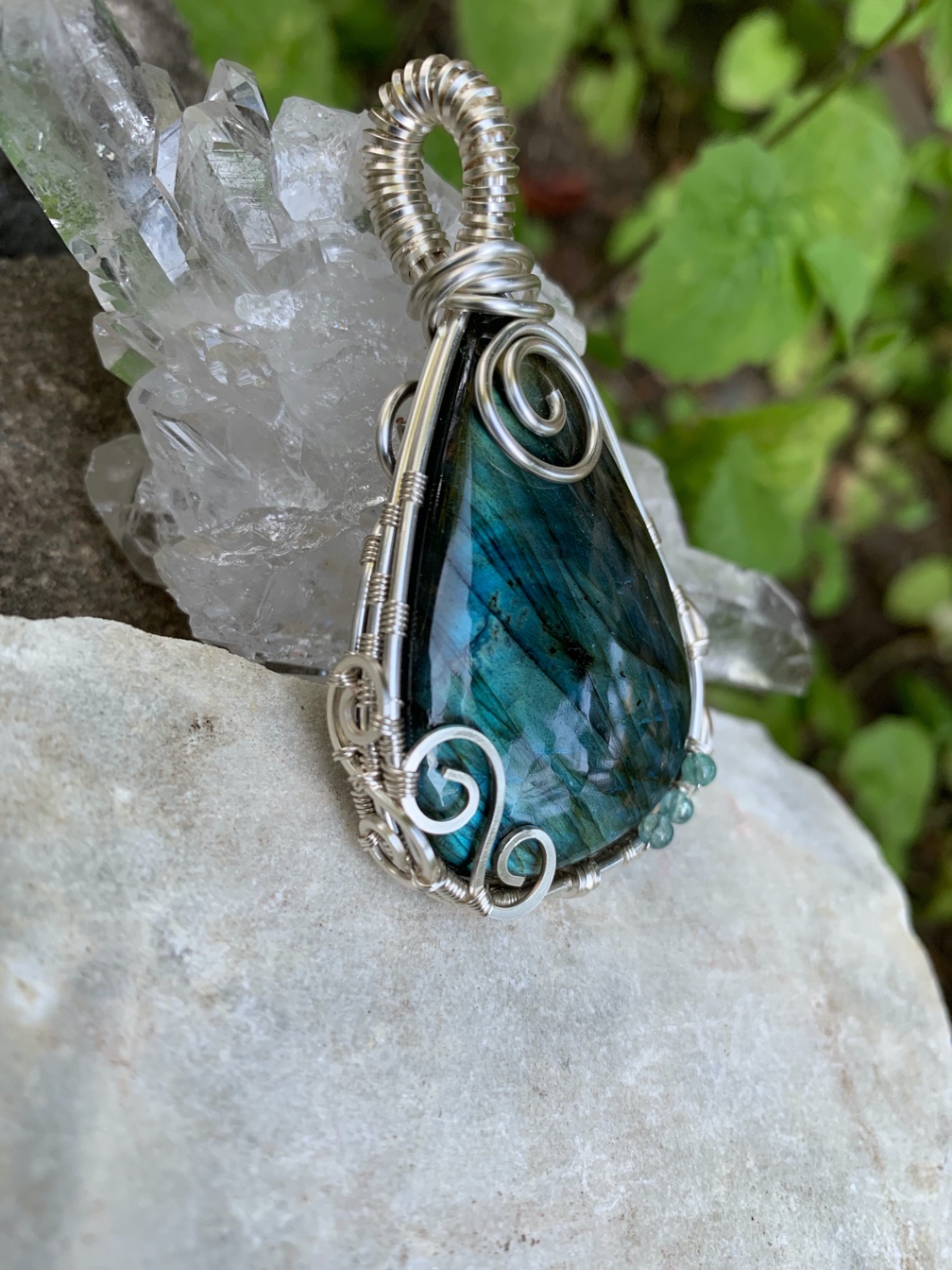 Turquoise stone ornately wrapped with silver-colored wire.